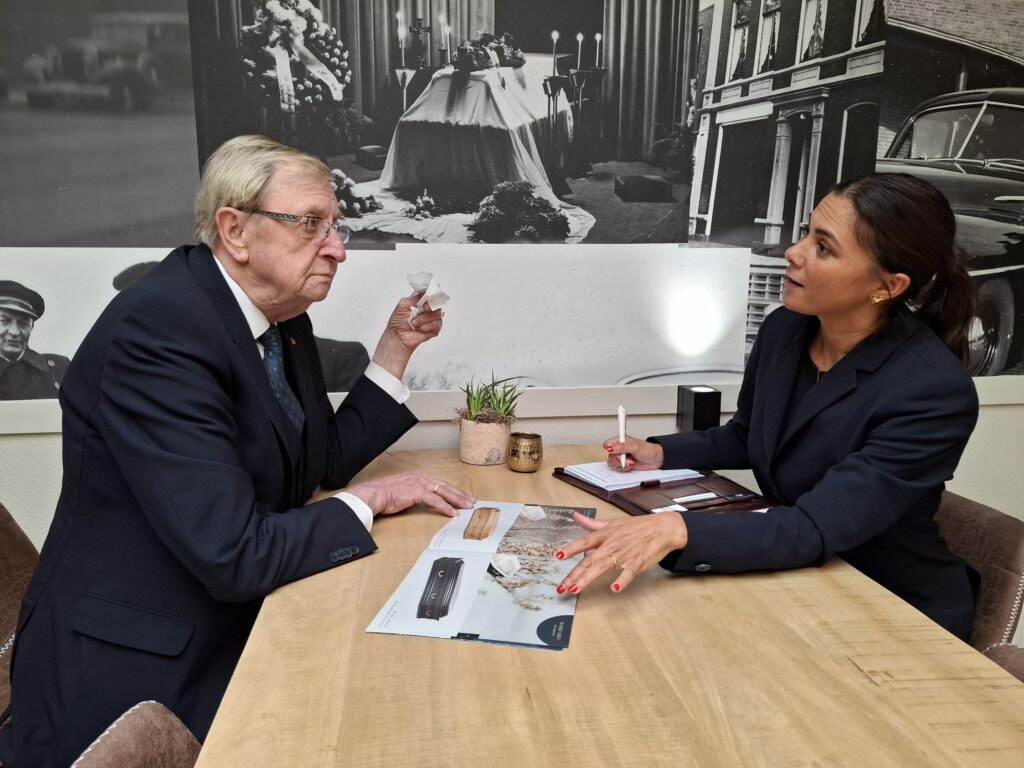 Adviseur en klant bespreken uitvaartwensen aan tafel