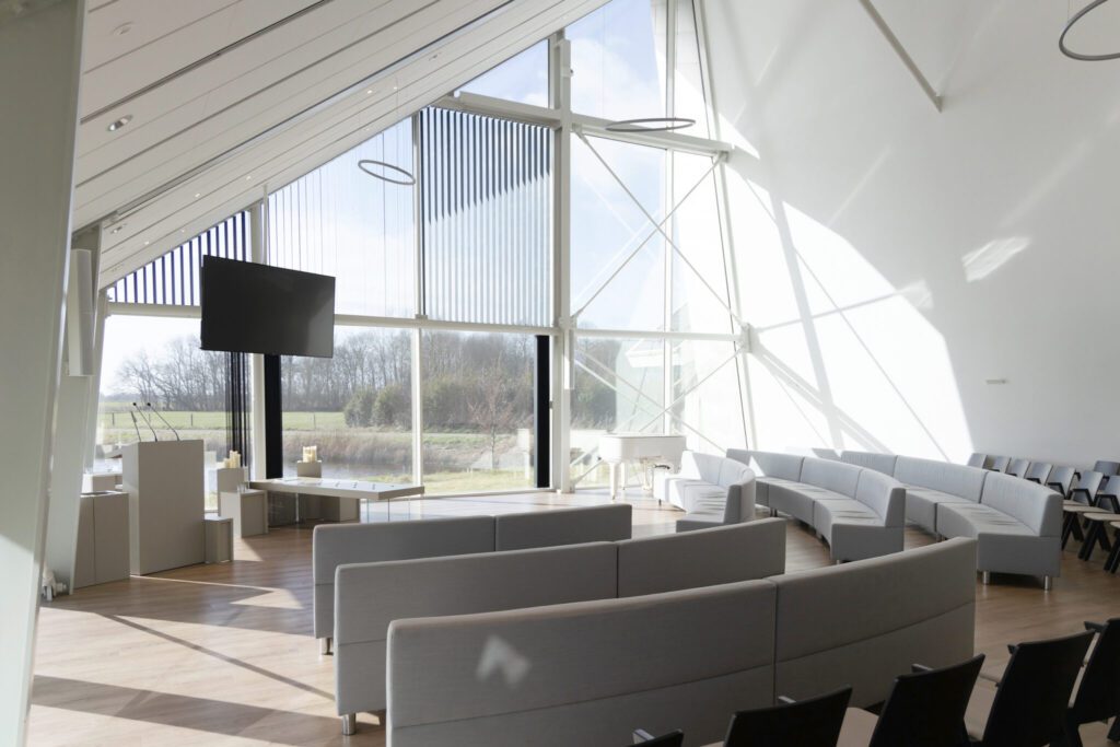 De lichte, moderne aula van Crematorium Alkmaar met weids uitzicht over het polderlandschap en een witte vleugel