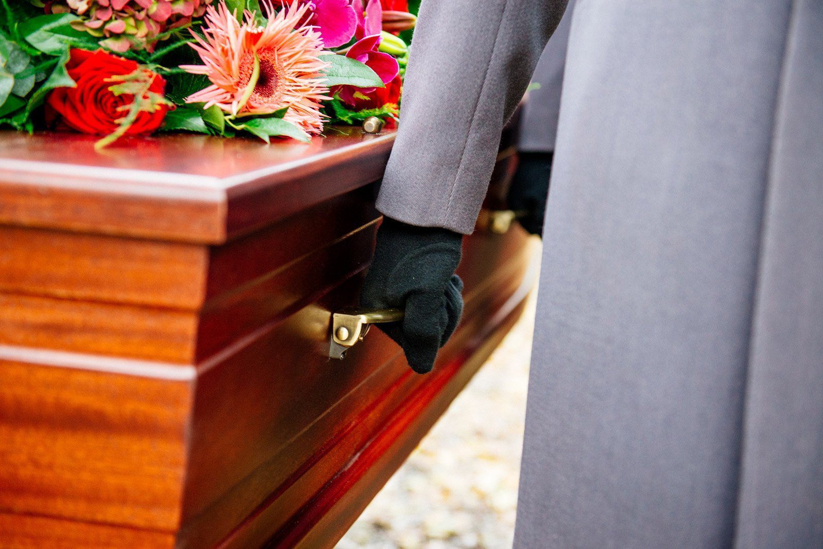 uitvaart regelen dragen van uitvaartkist met bloemen bij begrafenis