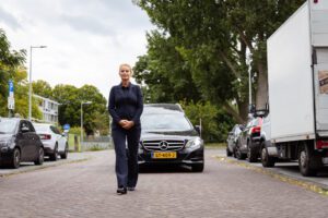 Uitvaartbegeleider loopt voor rouwauto tijdens uitvaart