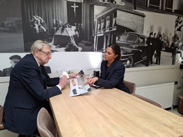 Adviseur bespreekt uitvaartmogelijkheden met klant aan tafel